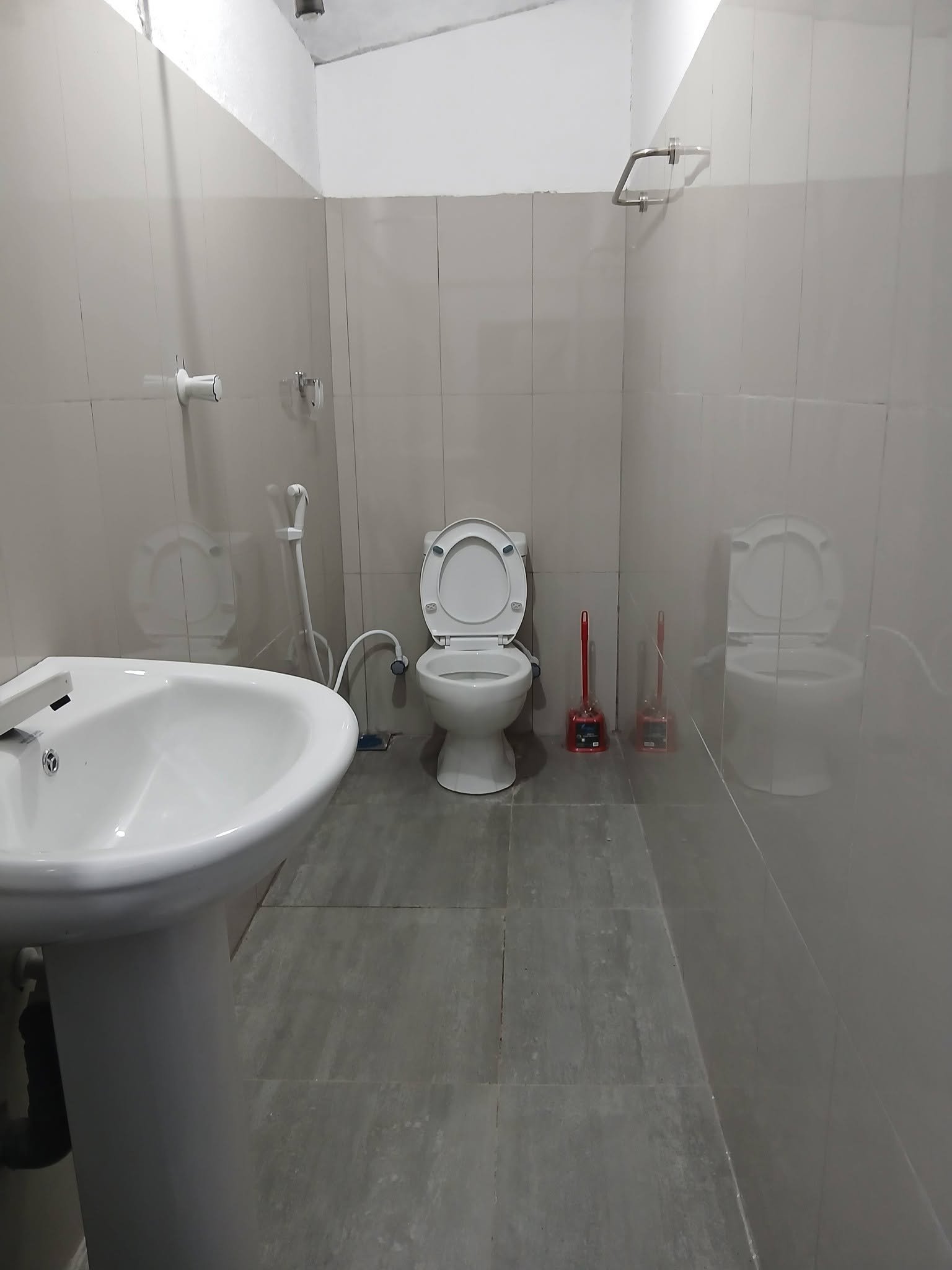 Clean tiled common bathroom with flush toilet and washbasin